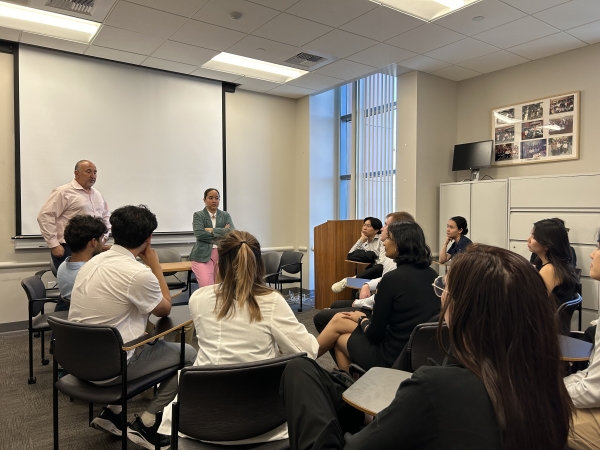 This is an image of students sitting in chairs in a circle facing the front of the room.